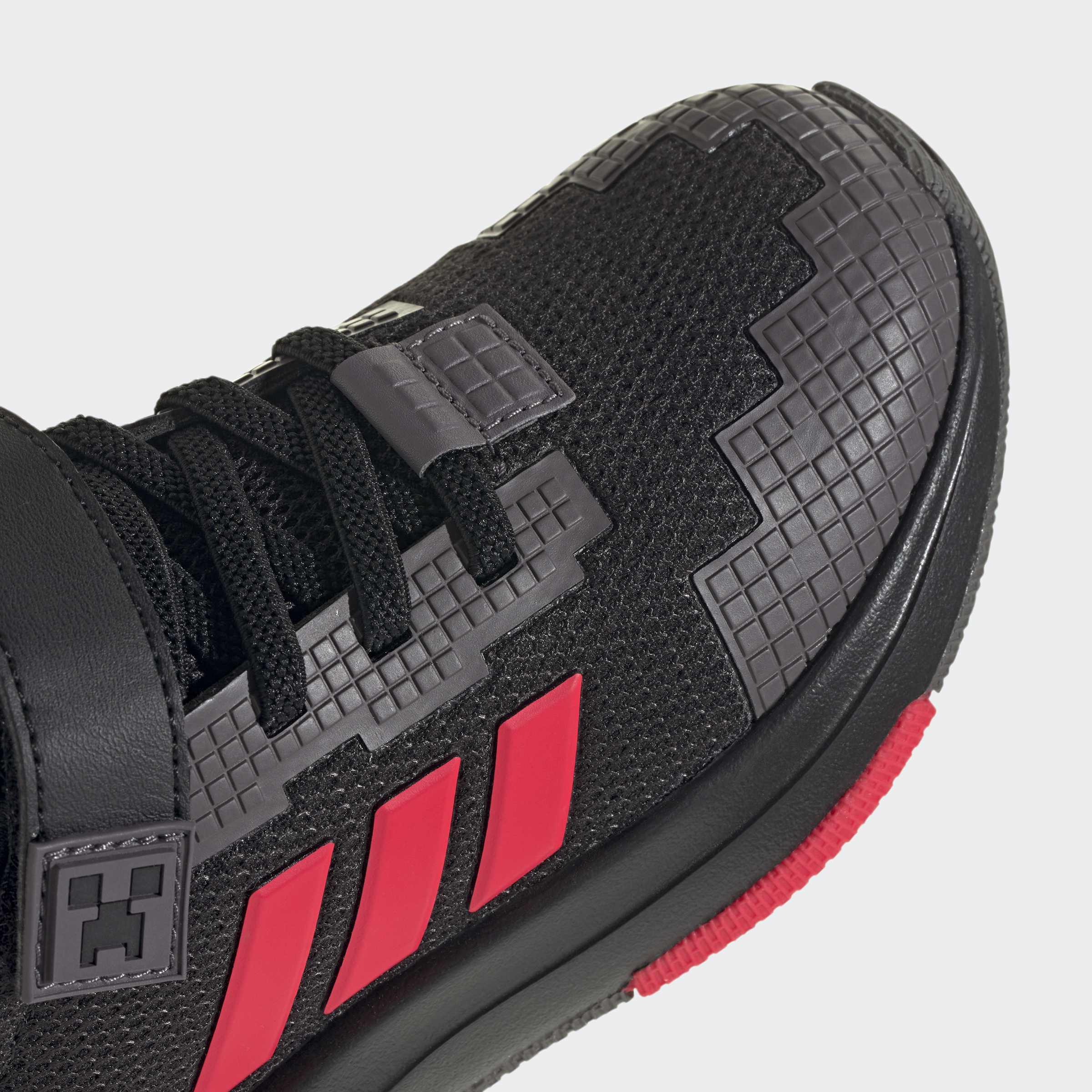 Детайл на Adidas Minecraft Pro – черна мрежеста материя, сиви пикселни подсилвания и три червени ленти